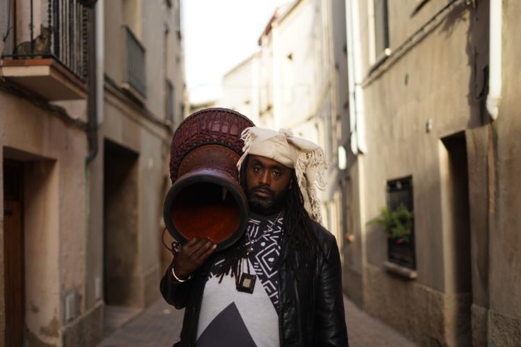 weedie braimah holding percussion standing in an alleyway in an old city