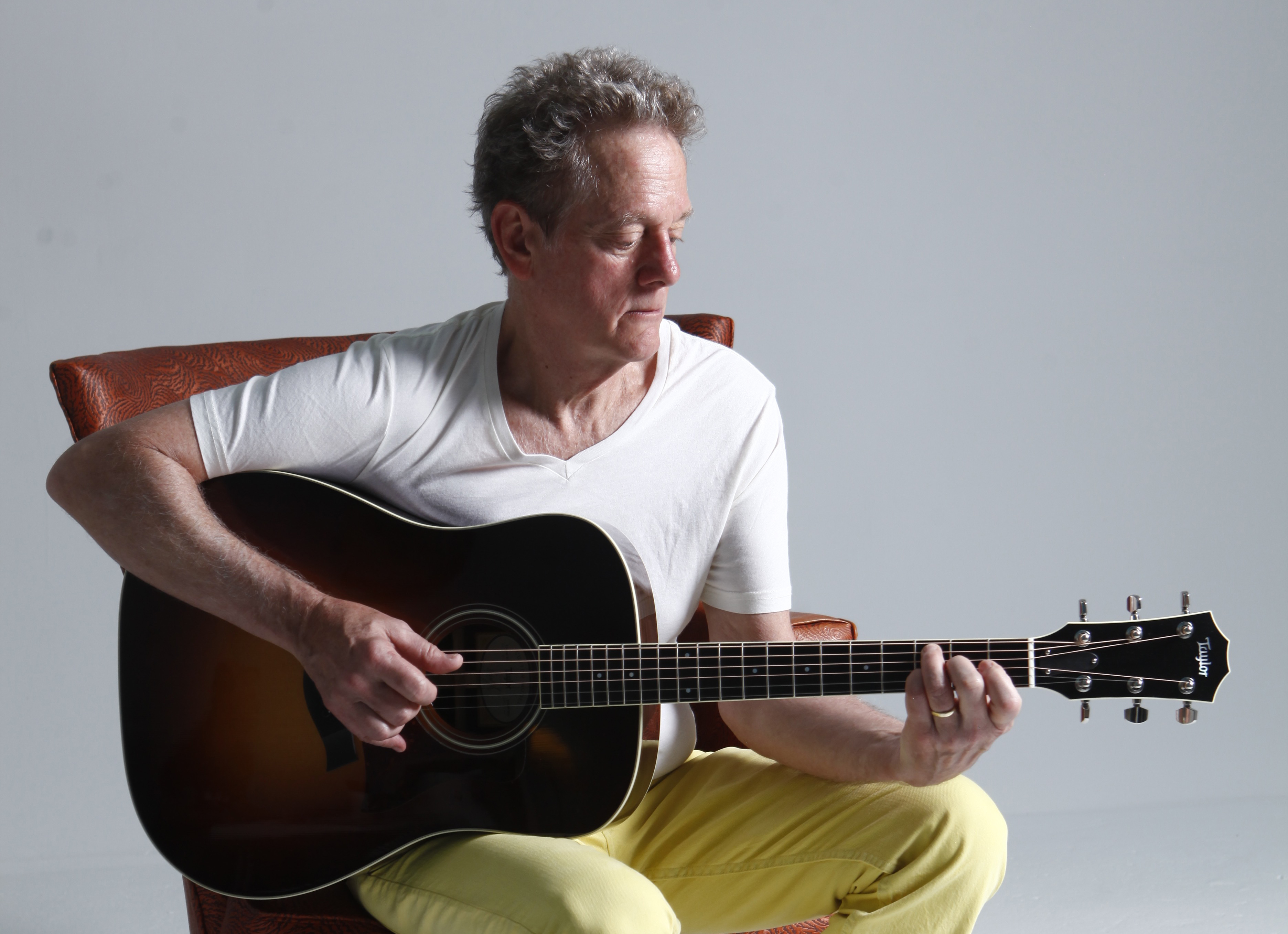 Photo of Professor Michael Bacon seated playing an acoustic guitar