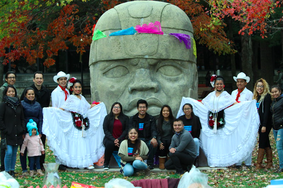 Guest performers and members of the Mexican Studies Institute at Lehman College pose with the Olmec head on campus.