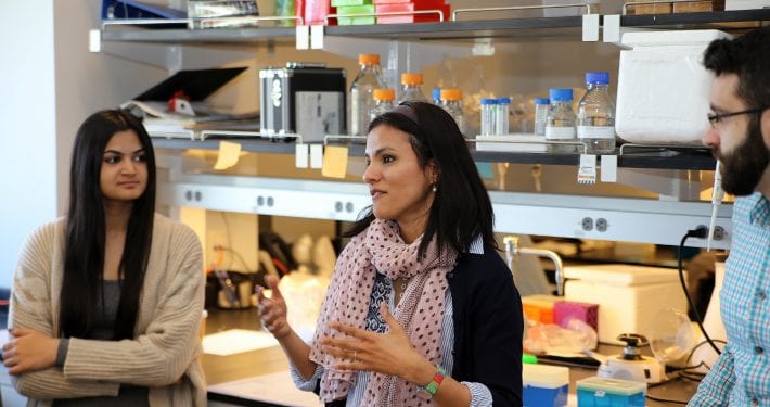 Woman talking with male and female students in a laboratory