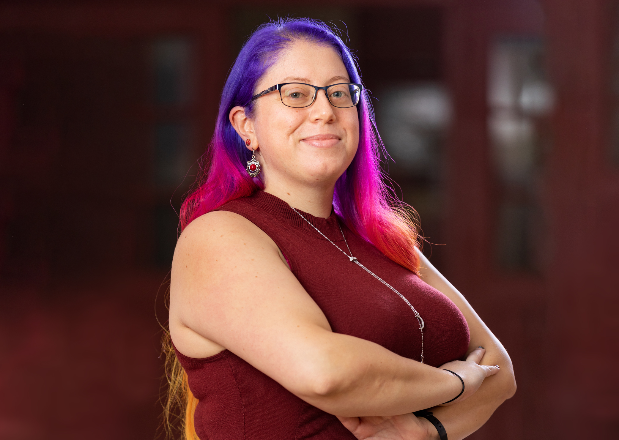 Women with purple and pink hair standing with arms crossed and smiling