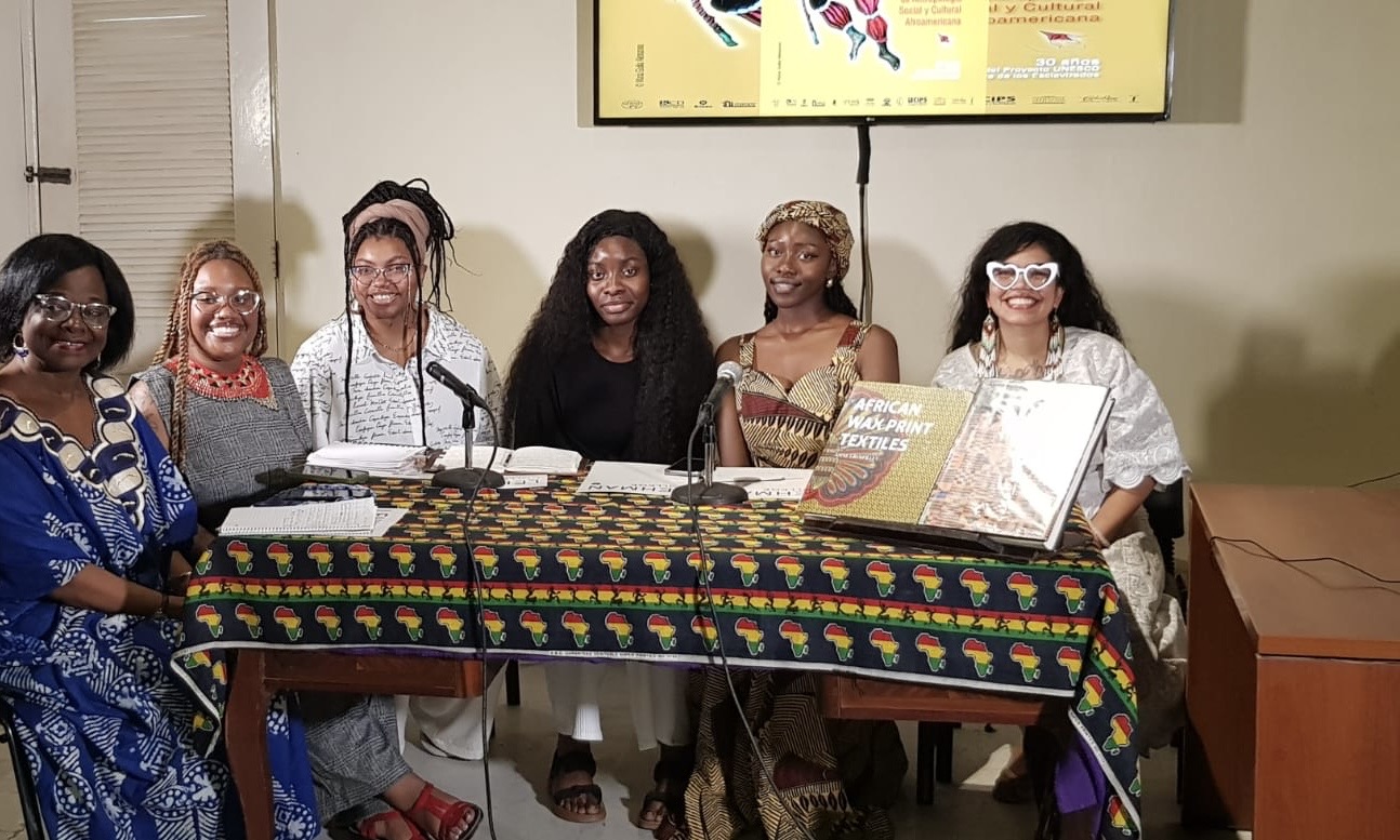 A group of women are sitting at a table facing the viewer.