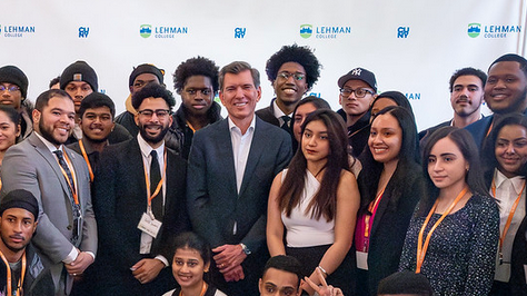 A group of people standing in front of a Lehman College banner.