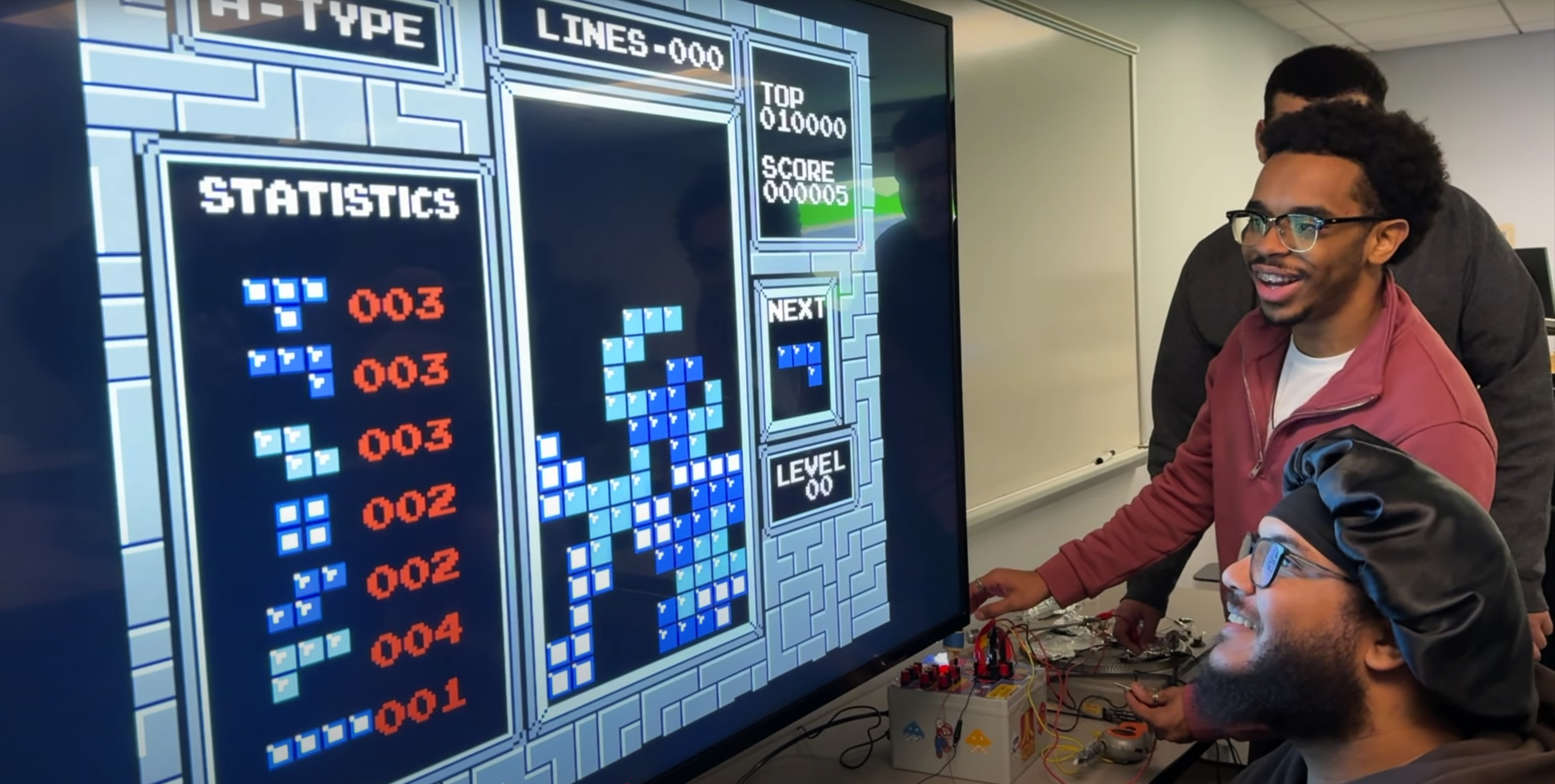 two students looking a a video game on a large screen.