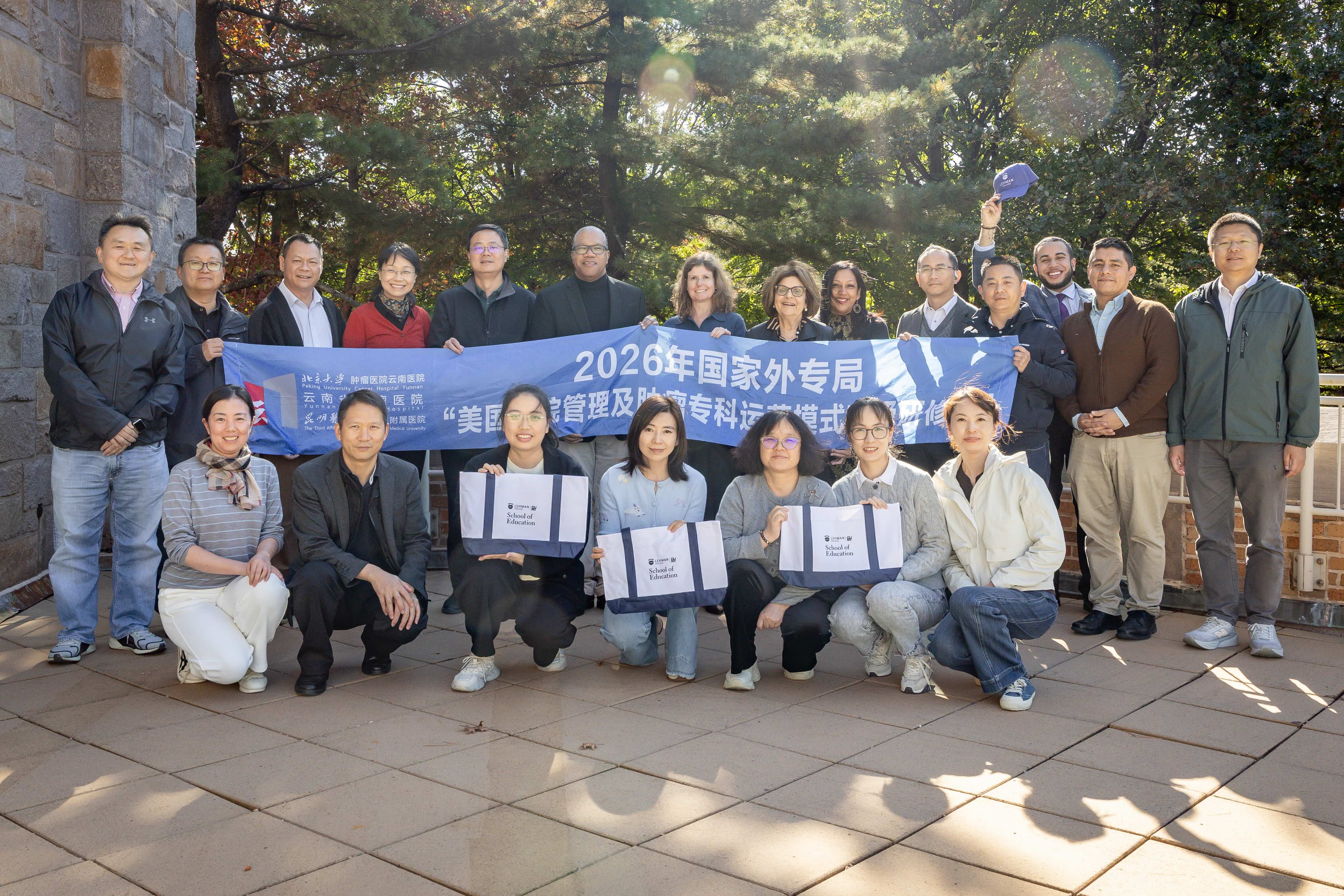 A group of Chinese healthcare leaders and Lehman faculty pose with a banner.