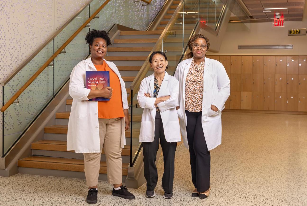 Nursing students in lab coats standing inside an academic building.