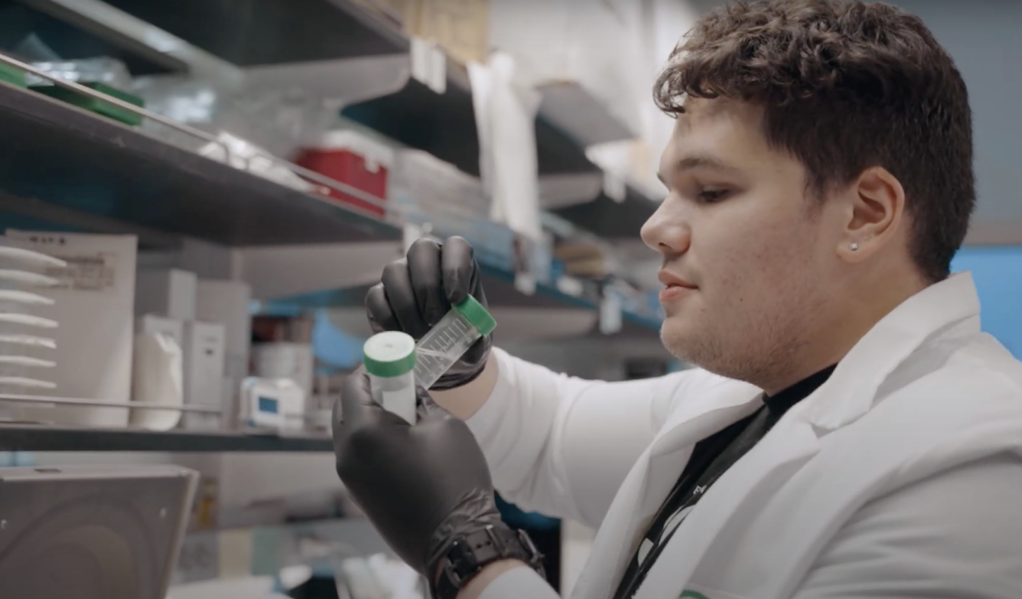 John in a lab wearing a white lab coat and working with medical supplies